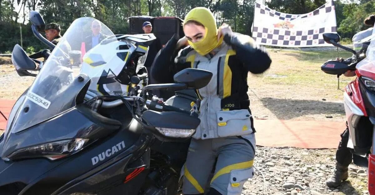 Iranian woman motorcyclist preparing her riding gear next to a Ducati