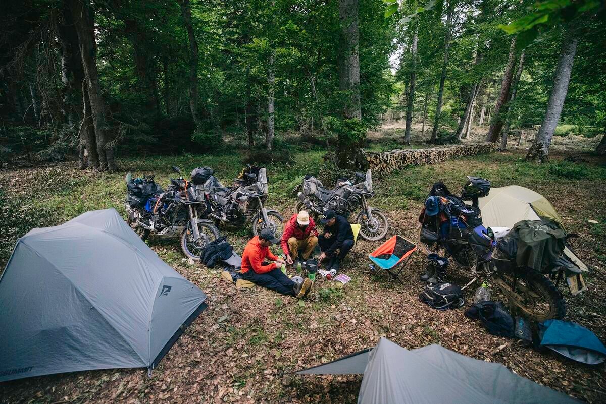 Motorcycle camping setup in a forest clearing with tents and bikes